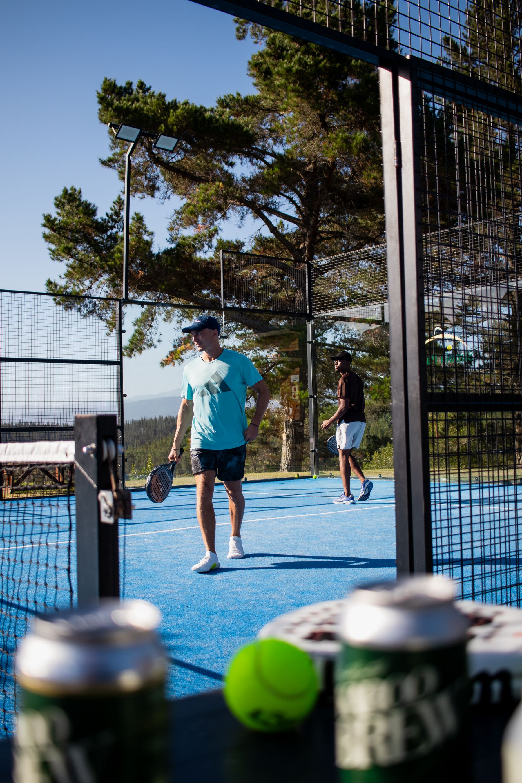 Padel players on a sunlit outdoor court